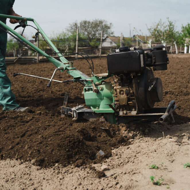 mężczyzna pokazuje, jak używać glebogryzarki na polu